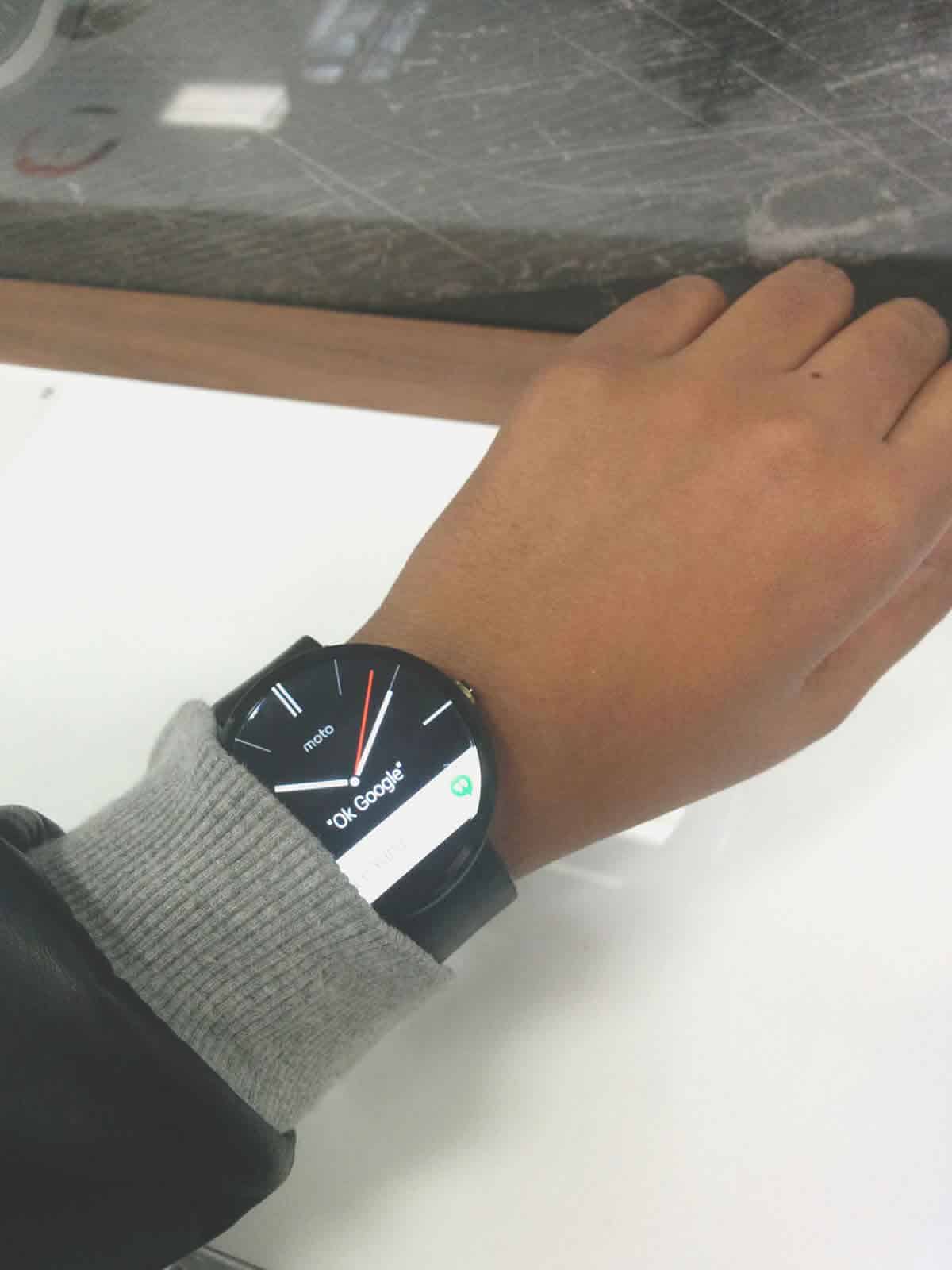 A black Moto watch displays the Android Wear mobile UI design.