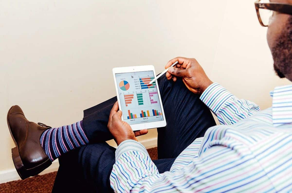 Back view of a businessman in a suit looking at a tablet screen with colorful graphs, the future of mobile app development lies in enterprise and not consumer apps.