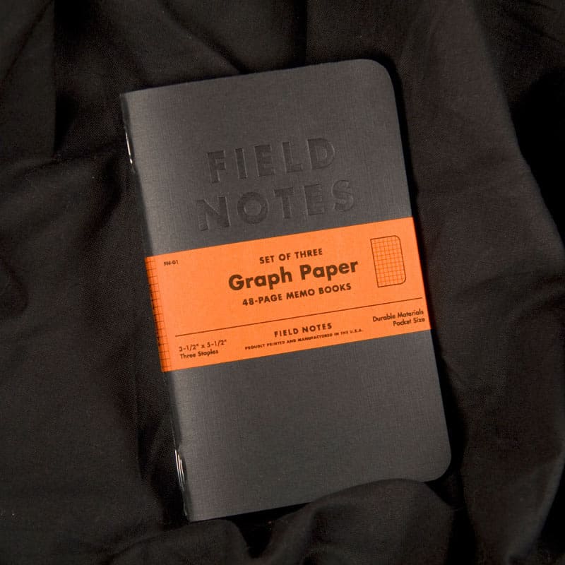 Field Notes notebooks for designers in black, placed on folded black fabric background.