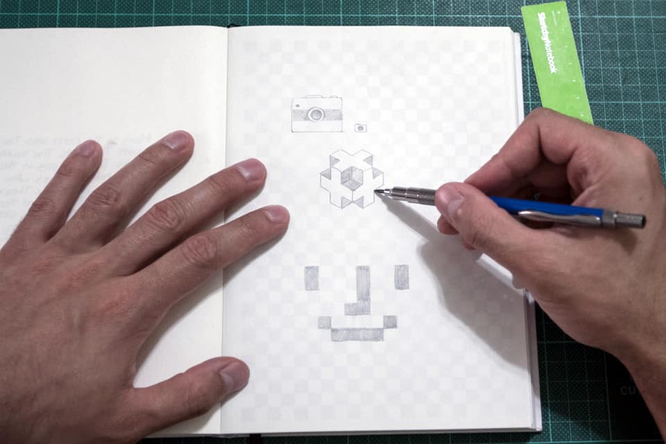 Person drawing cubes with a pen a page of a SketchyNotebook.