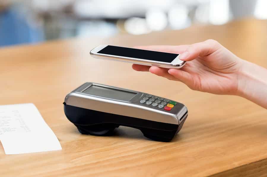 A photo of a person holding their phone above a credit card terminal while using the mobile pay feature.