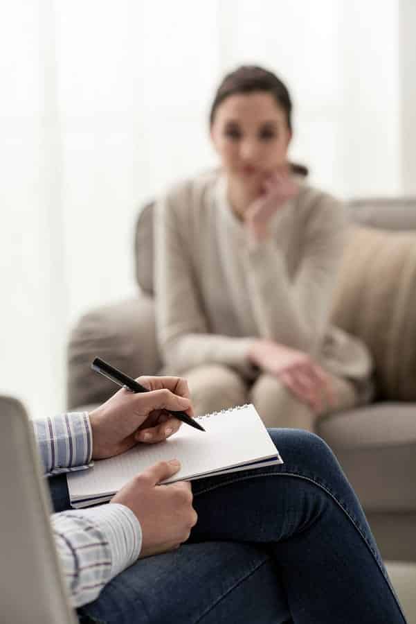 A photo of a therapist taking notes during a session with a patient.