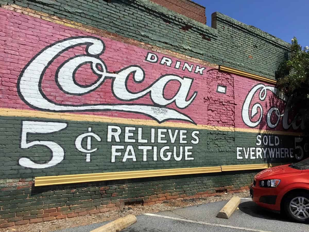 Uma foto de um anúncio velho de Coca-Cola pintado em um edifício de tijolo.