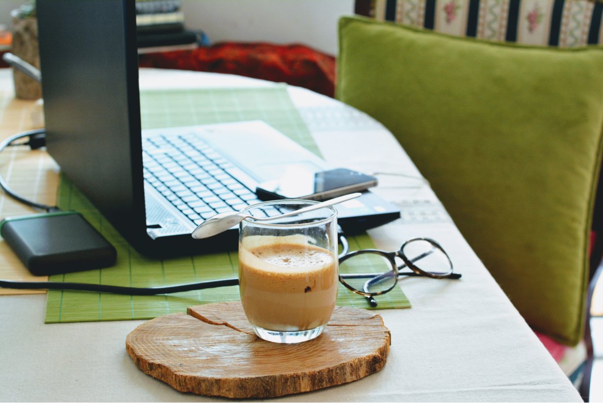 A photo of someone’s remote work station, complete with a laptop and a latte.